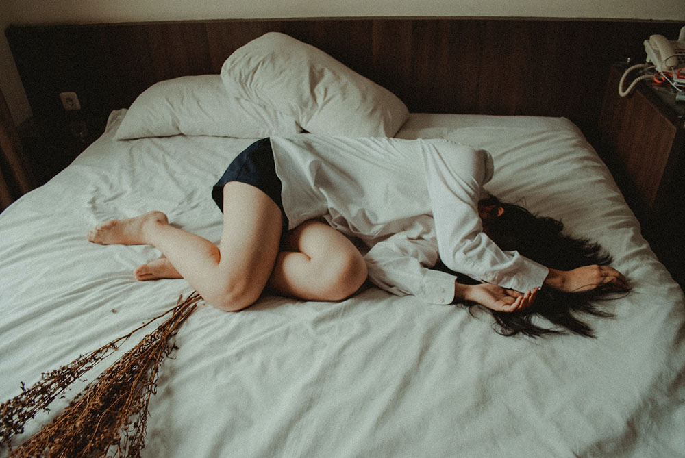 donna in posizione fetale sul letto che soffre