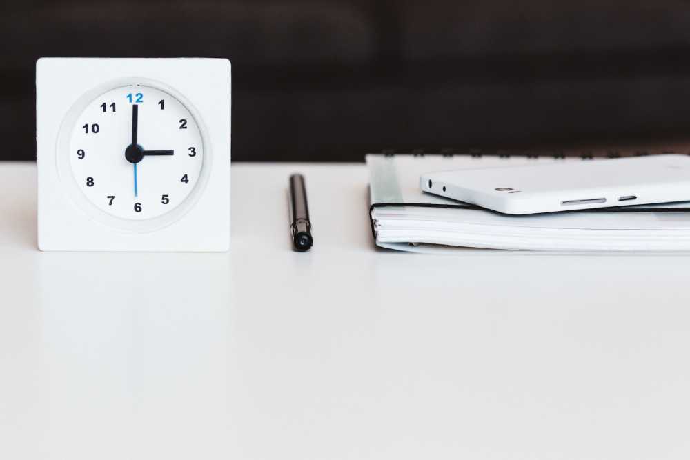 orologio su tavolo con penna e quaderno