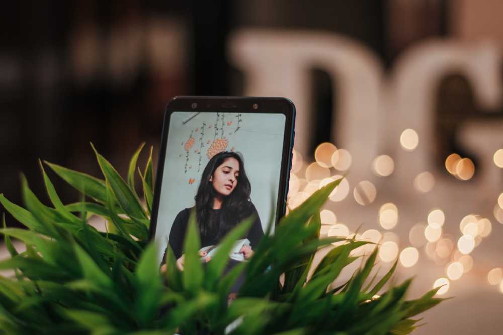 immagine di donna su cellulare in mezzo ai fiori