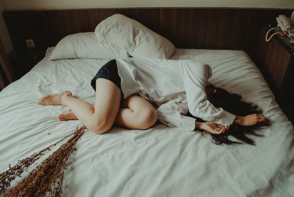donna rannicchiata sul letto sofferente