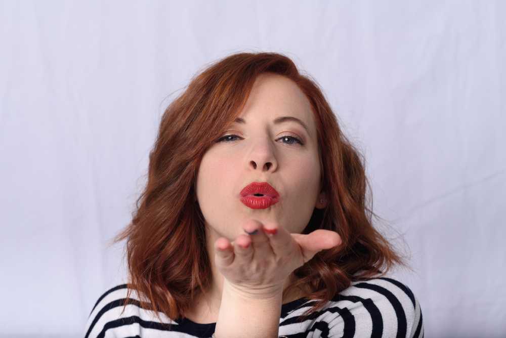 donna con capelli rossi che manda un bacio con la mano