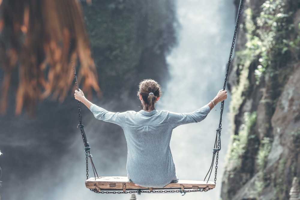donna su altalena di fronte ad una cascata