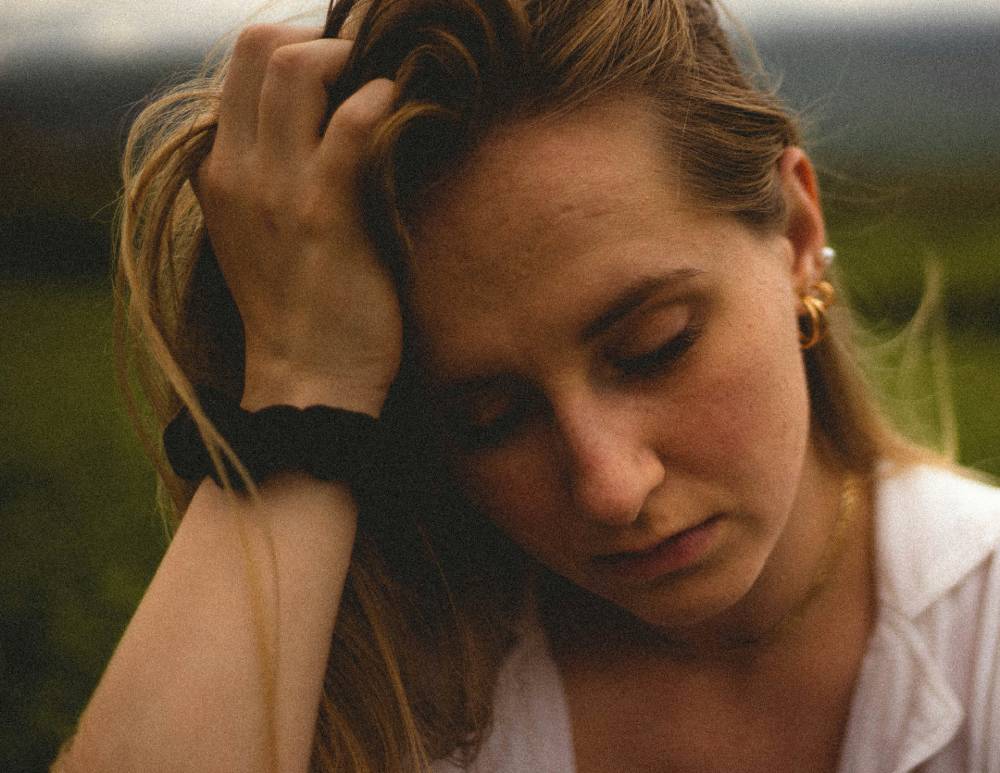 primo piano di donna che si tiene la testa e guarda in basso