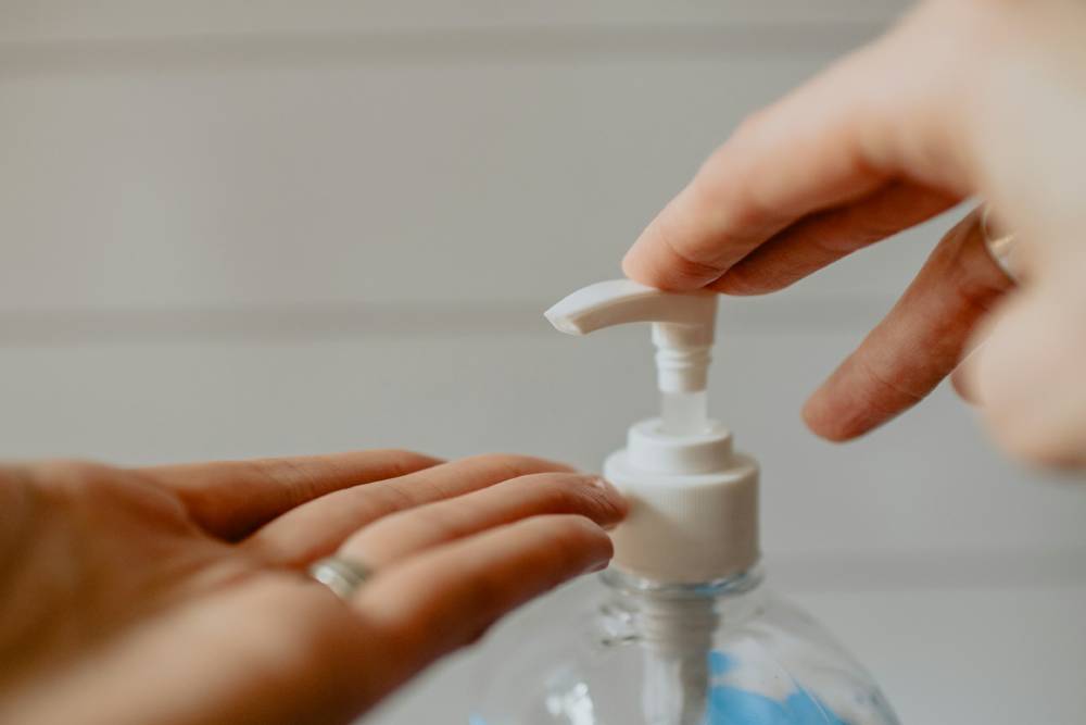 una mano schiaccia un erogatore di sapone e l'altra è tesa sotto l'erogatore