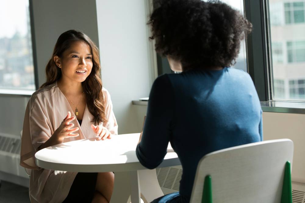 due donne sedute ad un tavolo che parlano