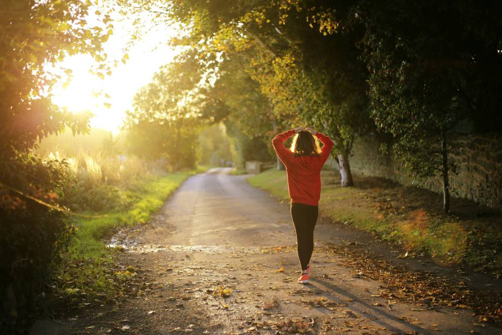 donna di spalle che cammina in un parco con le mani sulla testa