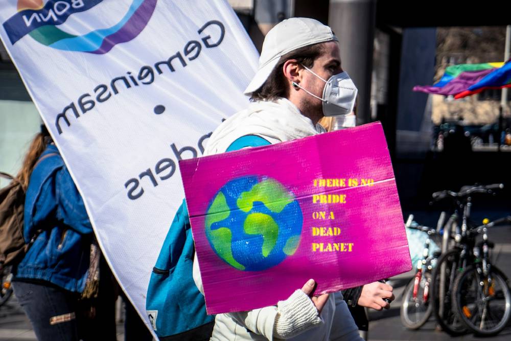 ragazzo per strada con mascherina che manifesta con un cartello