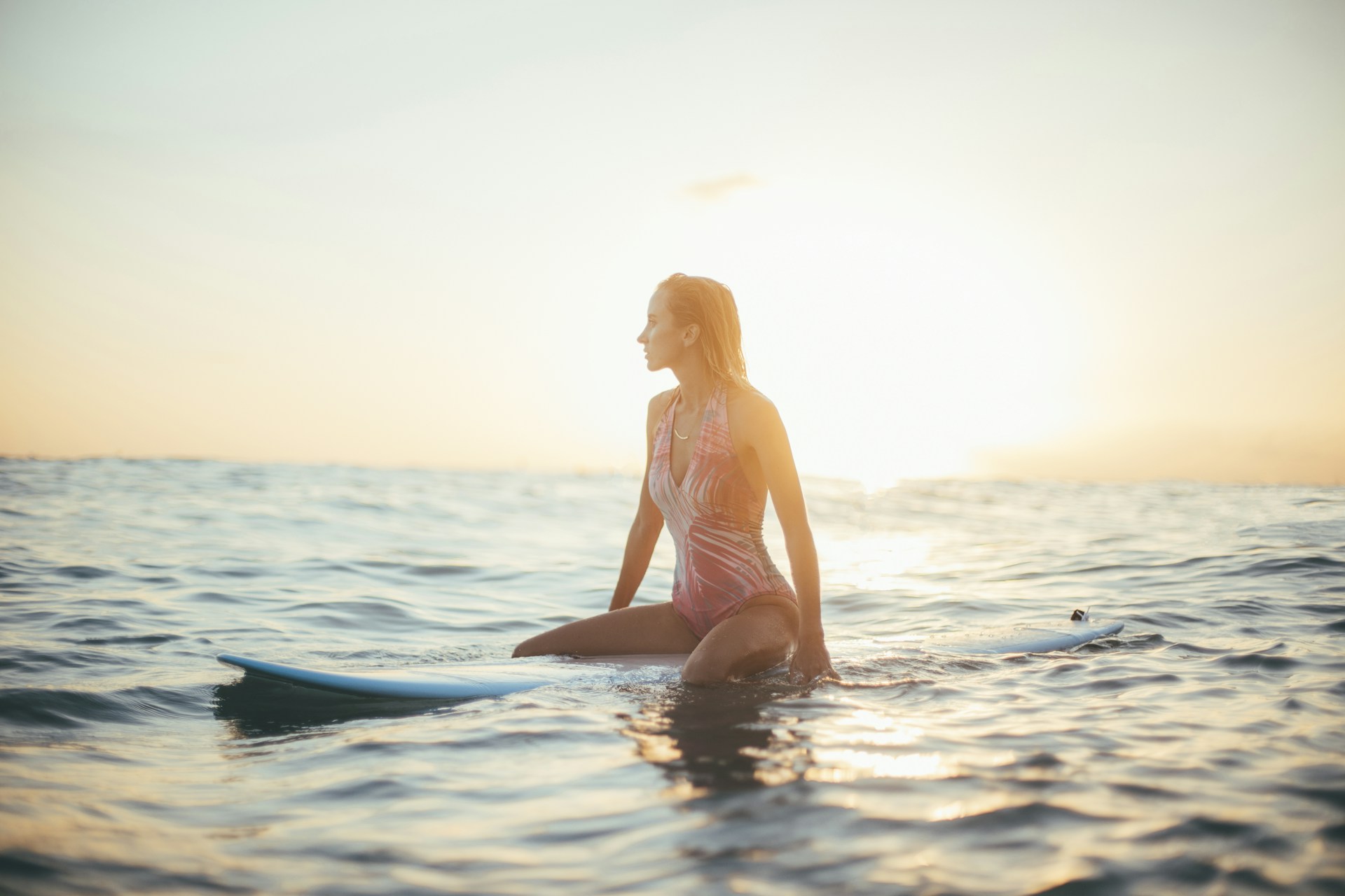 donna su tavola da surf seduta in mezzo al mare